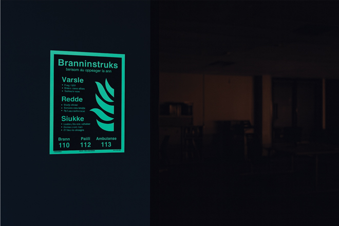 Etterlysende branninstruks lyser tydelig i mørket og viser trinn for varsling, redning og slukking