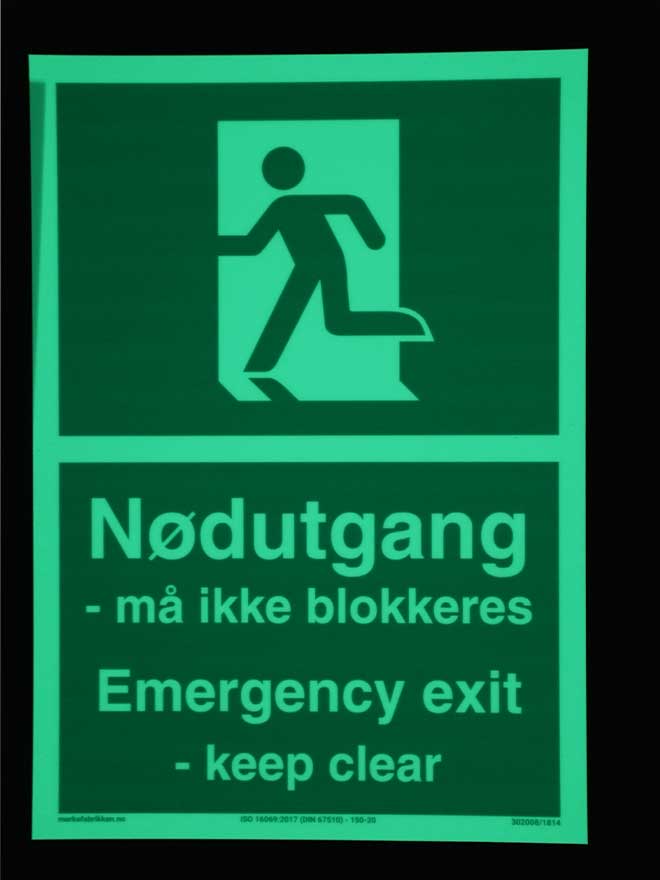 Selvlysende skilt som med symbol og tekst informerer om at nødutgang ikke må blokkeres