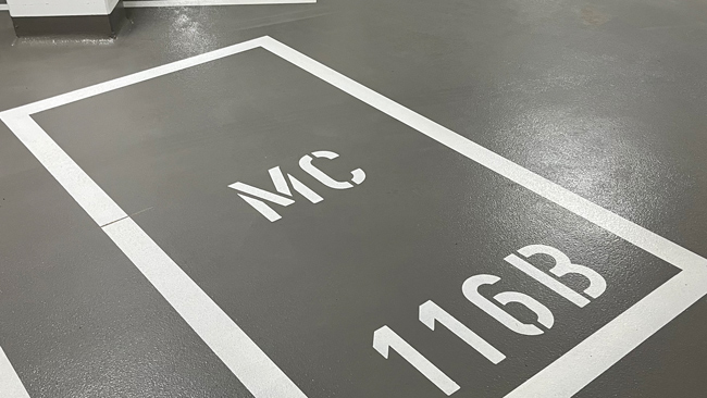 MC-parkeringsplass oppmerket med tall og bokstaver ved bruk av sjablonger